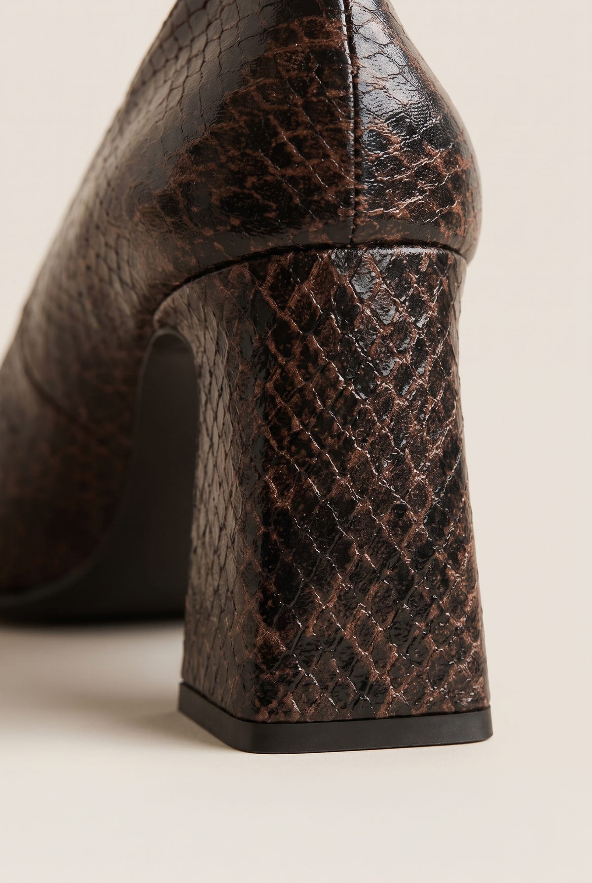 Close-up of brown snake-print leather on flared block heel showing scale texture and dark sole