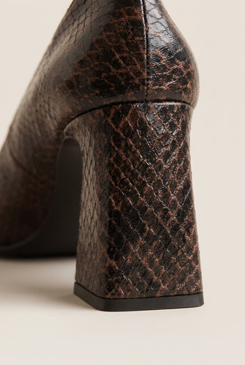Close-up of brown snake-print leather on flared block heel showing scale texture and dark sole