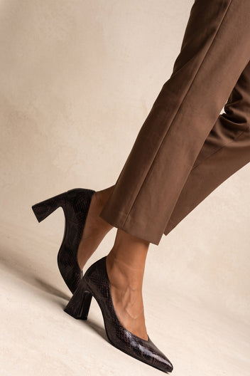 Model in brown trousers stepping forward in brown snake-print pumps showing flared block heel