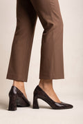 Model wearing brown snake-print pointed-toe pumps with flared block heels and brown trousers