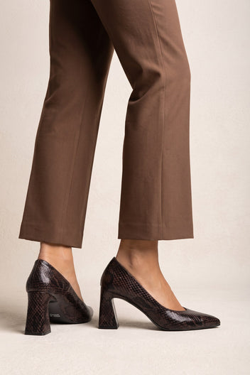 Model wearing brown snake-print pointed-toe pumps with flared block heels and brown trousers