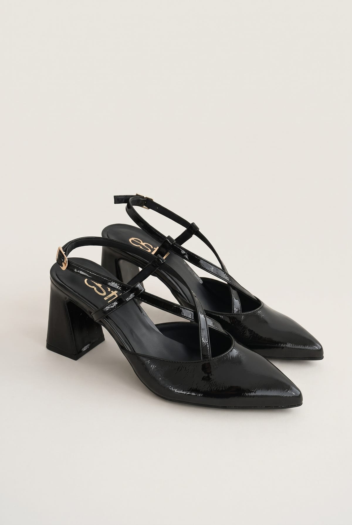 Angled pair of glossy black patent block heel pumps with crossed straps and pointed toes