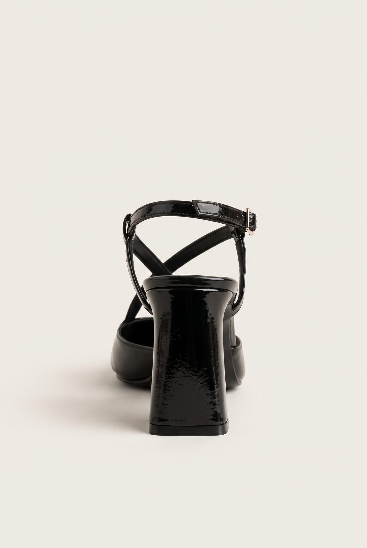 Back view of a brown patent slingback pump showing the narrow crossed straps at the heel counter and the tall block heel