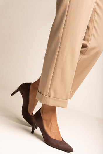 Close-up of brown suede stiletto pump with thin heel beside rolled beige trousers