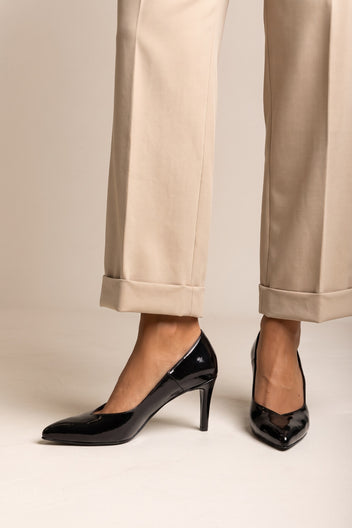 Black patent pointed toe stiletto pump with slim heel, front view of the pair with beige trousers