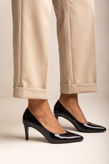 Black patent pointed toe stiletto pump with high heel, pair worn with beige trousers
