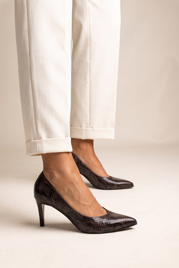 Front view of model in brown snake print stiletto pumps with pointed toes and cream trousers