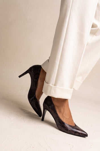 Model in brown snake print stiletto pumps seen from the side with a slim heel and cuffed trousers