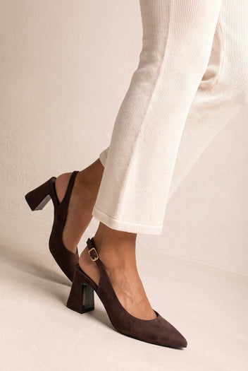 Model wearing brown suede slingback pumps with pointed toes and block heels, paired with cream trousers and one leg forward
