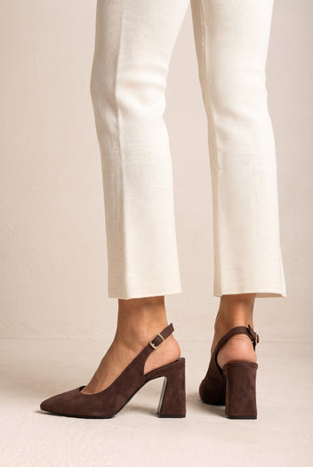 Model wearing brown suede slingback pumps with cream trousers, legs seen from mid-calf down with the buckled straps visible