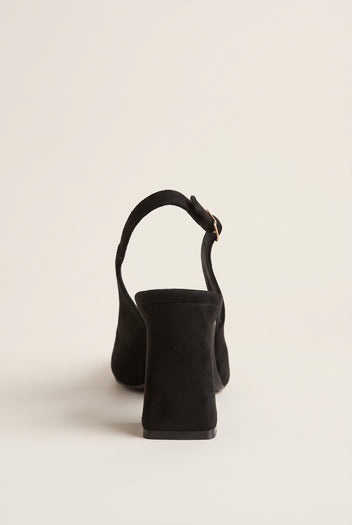Back view of a black suede slingback pump showing its block heel, heel counter and slim buckled strap