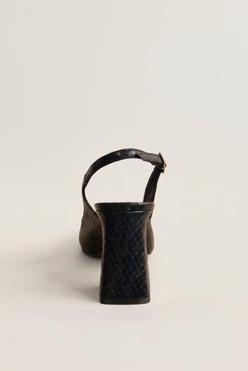 Back view of a black snake-embossed slingback pump showing its block heel and slim ankle strap with a gold buckle
