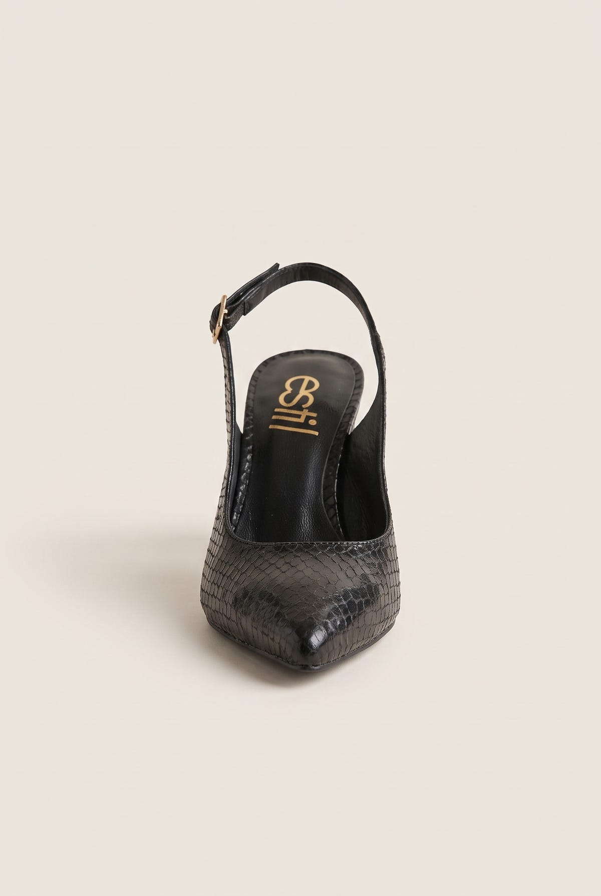 Front view of a black snake-embossed slingback pump with a pointed toe and a gold-tone buckle strap resting on its heel