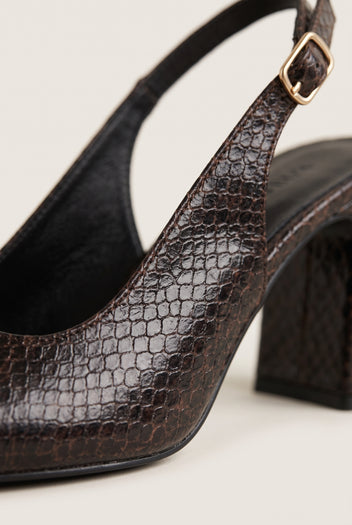 Close-up of brown snake-embossed leather on a slingback pump with a gold buckle strap and sculpted block heel