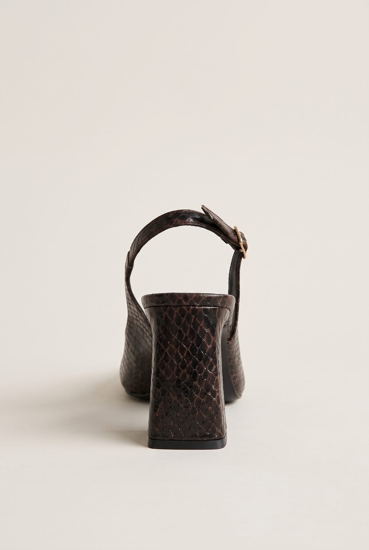 Back view of a brown snake-print slingback pump with a block heel and a buckled strap curving over the heel counter