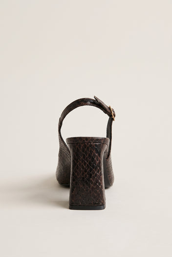 Back view of a brown snake-print slingback pump with a block heel and a buckled strap curving over the heel counter