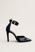 Side view of a black patent stiletto pump with a pointed toe, slim high heel and gold buckled ankle strap