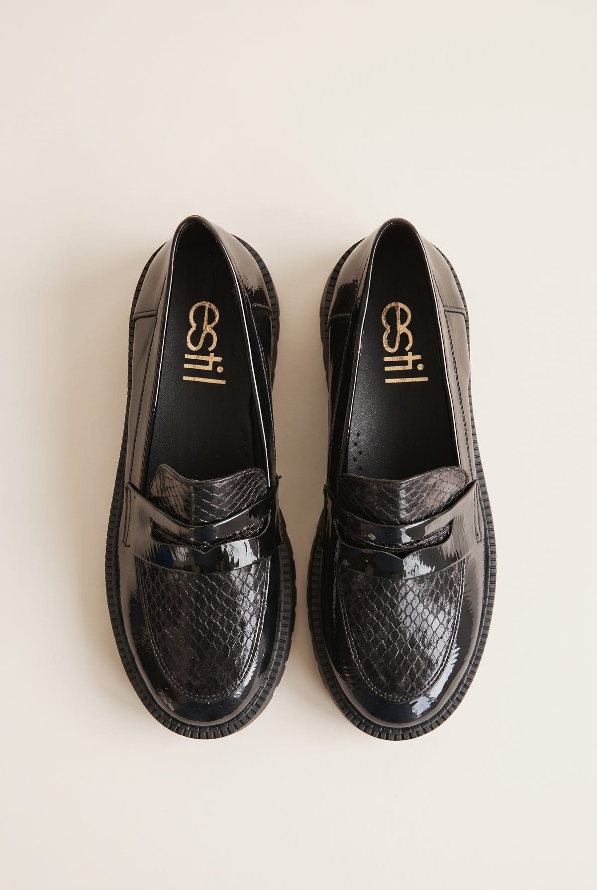 Top view of black patent chunky loafers with snake-embossed vamp and penny strap placed side by side