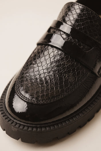 Close-up of black patent leather loafer vamp with snake-embossed texture and lug sole edge