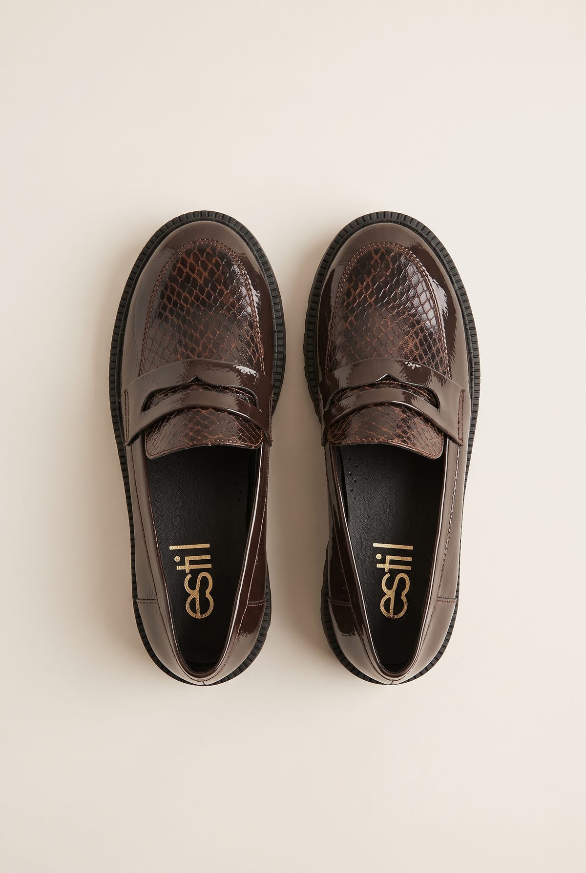 Top view of brown patent snake-embossed chunky loafers placed side by side with penny straps