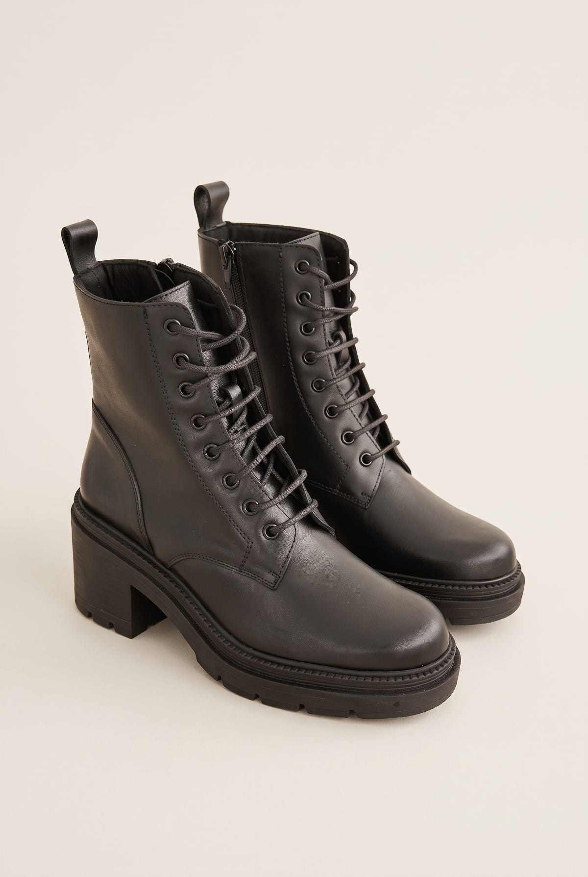 Pair of black leather lace-up ankle boots with side zips, pull tabs and chunky block heels with lug soles, three-quarter view