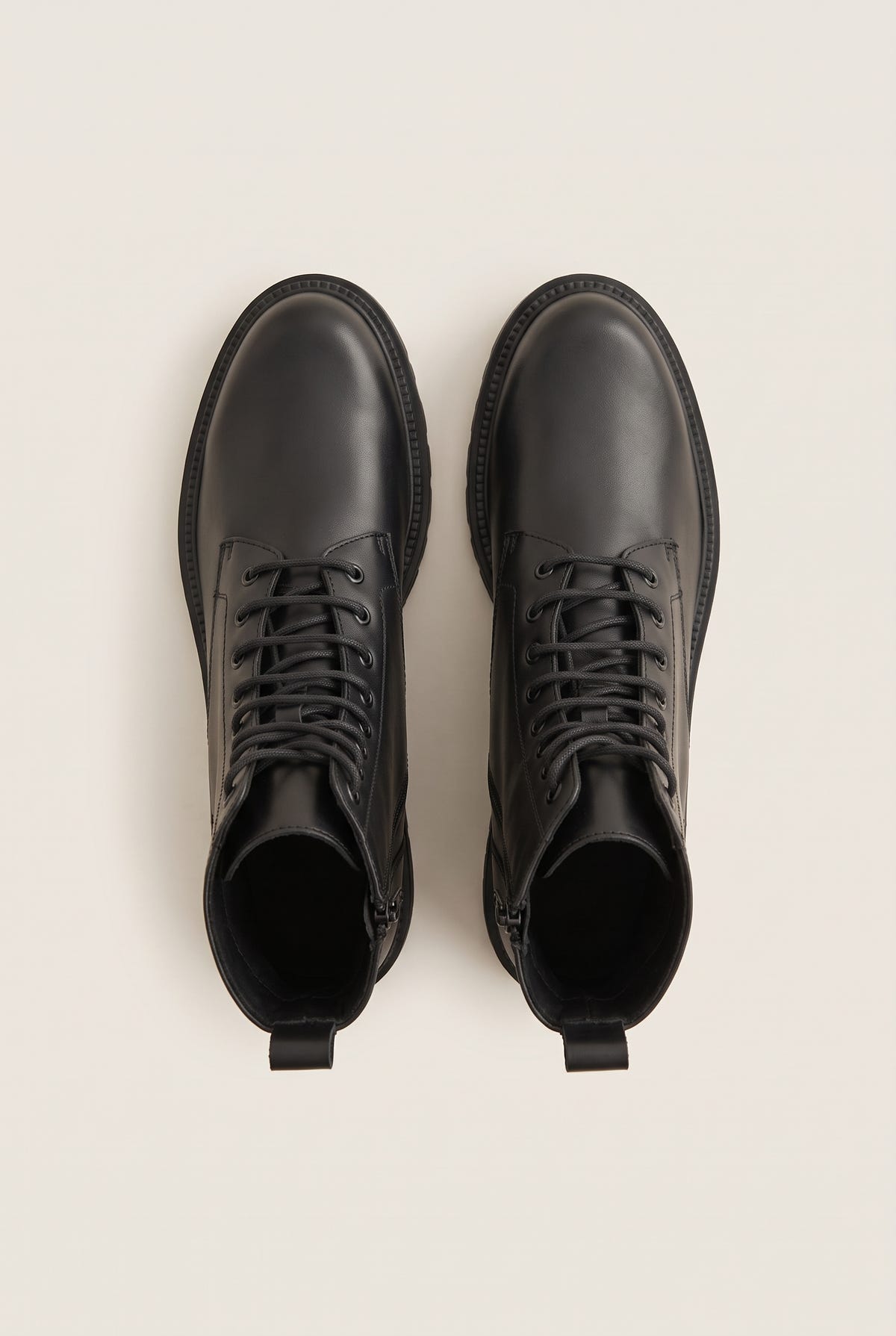 Top-down view of a pair of black leather lace-up boots with black laces, side zips and back pull tabs
