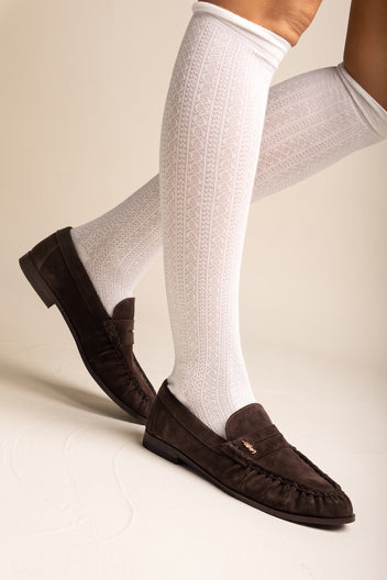 Model wearing brown suede flat loafers with pleated vamp and white knee-high socks seen from the side