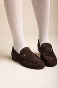 Brown suede penny loafers with pleated vamp worn with white knee-high ribbed socks in side view