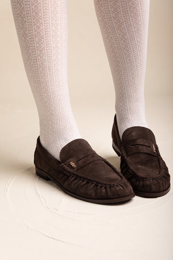 Brown suede penny loafers with pleated vamp worn with white knee-high ribbed socks in side view