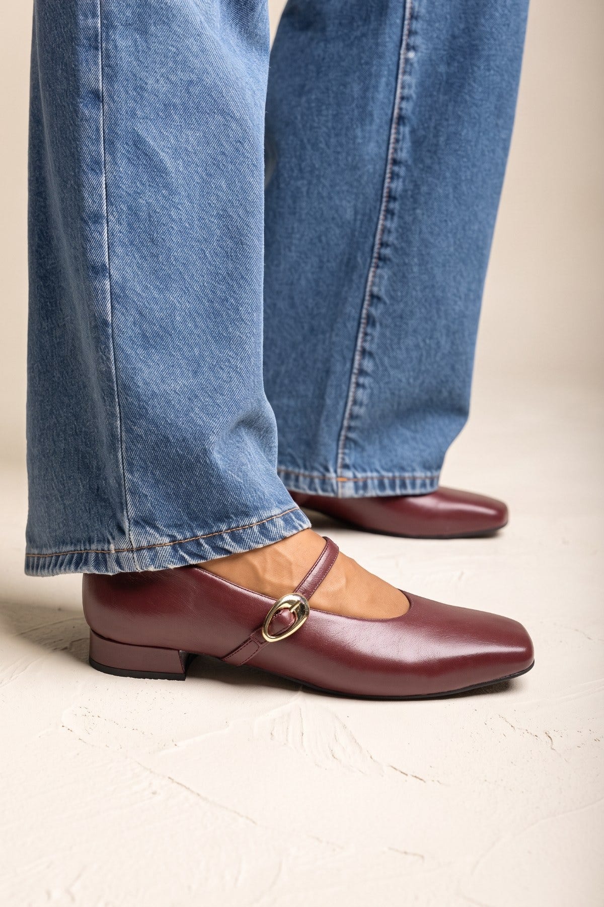 Bordeaux matte square toe Mary Jane flat with thin strap, side view on model in jeans