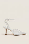 Side view of a white lace pump with a thin ankle strap, buckle closure and a slim stiletto heel