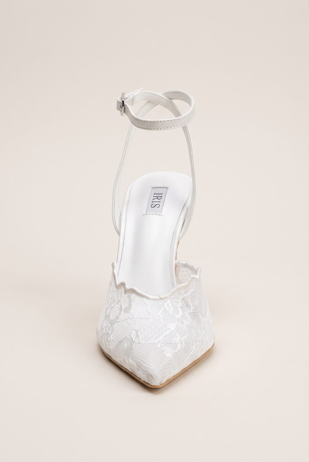 Front view of a white lace pump with ankle strap loops rising behind the lace-trimmed vamp