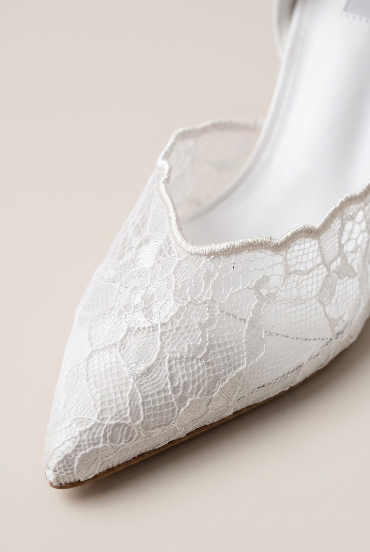 Close-up of white lace detail along the pointed toe and vamp edge of a stiletto pump