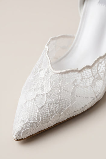 Close-up of white lace detail along the pointed toe and vamp edge of a stiletto pump