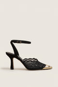 Side view of black lace detail stiletto pump with gold-toned pointed cap toe and ankle strap