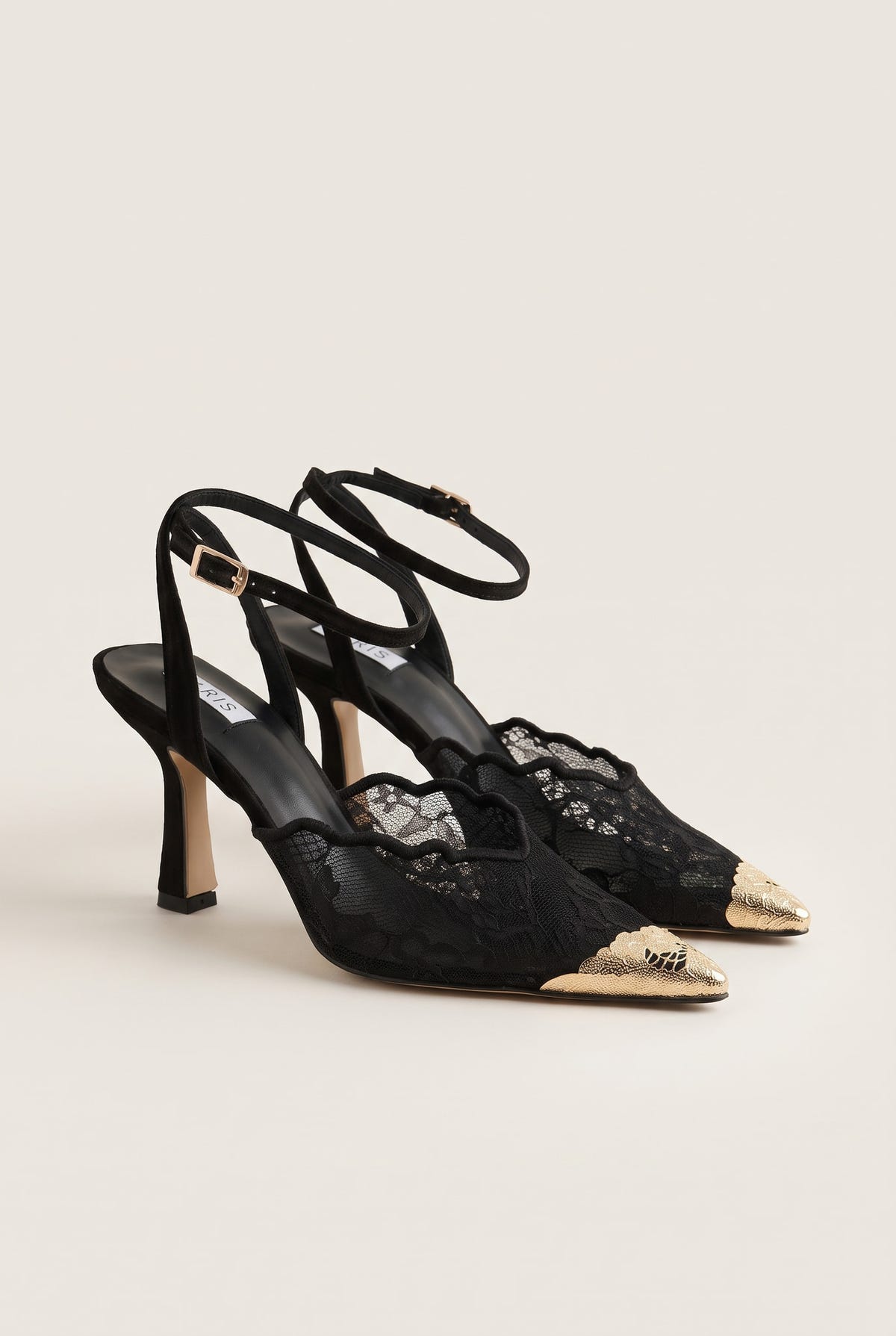 Angled pair of black lace stiletto pumps with gold-toned pointed toe caps and slim heels