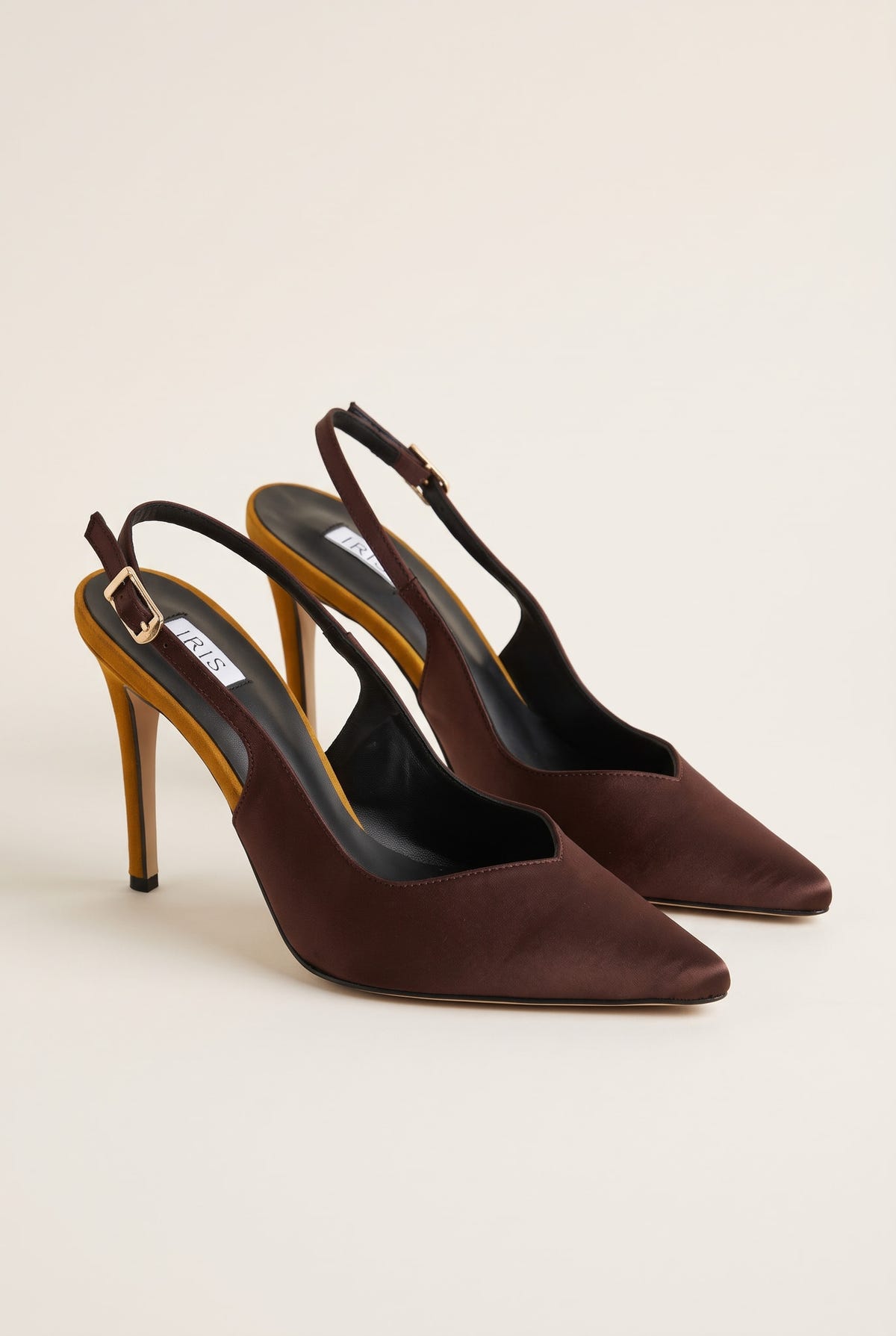 Pair of brown satin slingback pumps seen at an angle with gold heels and buckled ankle straps