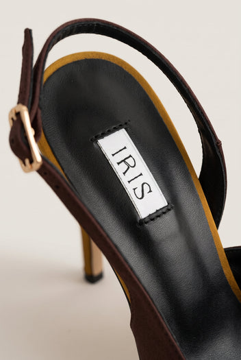 Close-up of a brown satin slingback strap with a gold buckle and the dark insole behind it