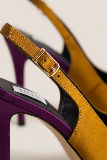Close-up of an olive satin strap with a gold buckle beside a purple heel and dark insole