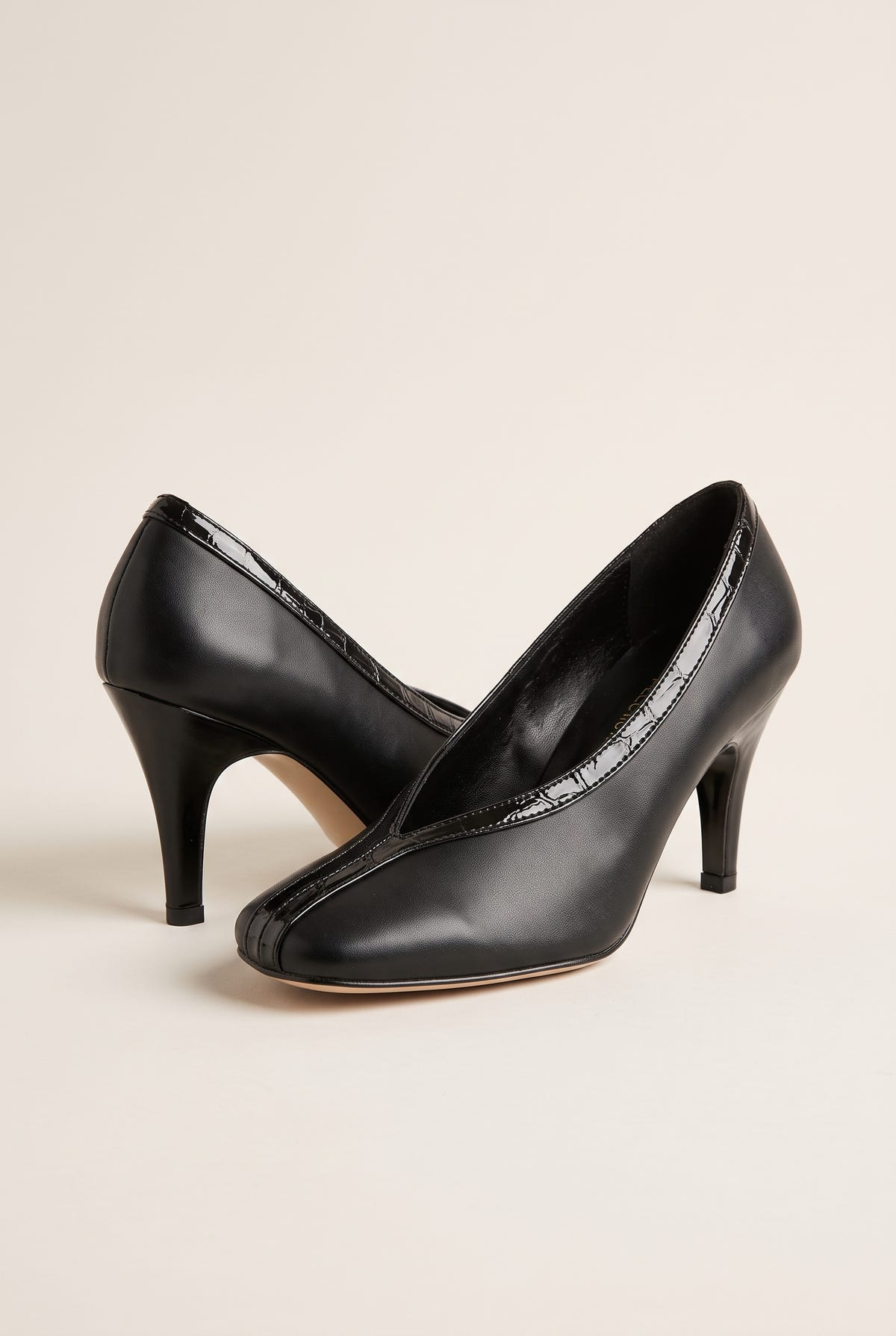 Three-quarter view of a pair of black smooth court shoes with V-cut vamps, croc-effect trim and high heels