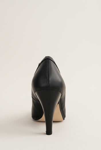 Back view of black court shoe showing the stitched heel seam and a tapered high heel