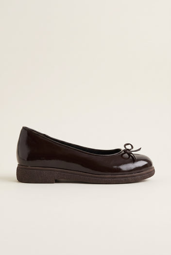 side view of one glossy dark brown patent ballet flat with a low thin sole and a small bow at the vamp