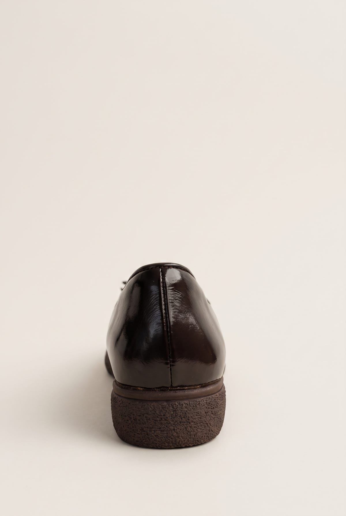 back view of one glossy dark brown patent ballet flat showing the heel counter and a thick ridged sole