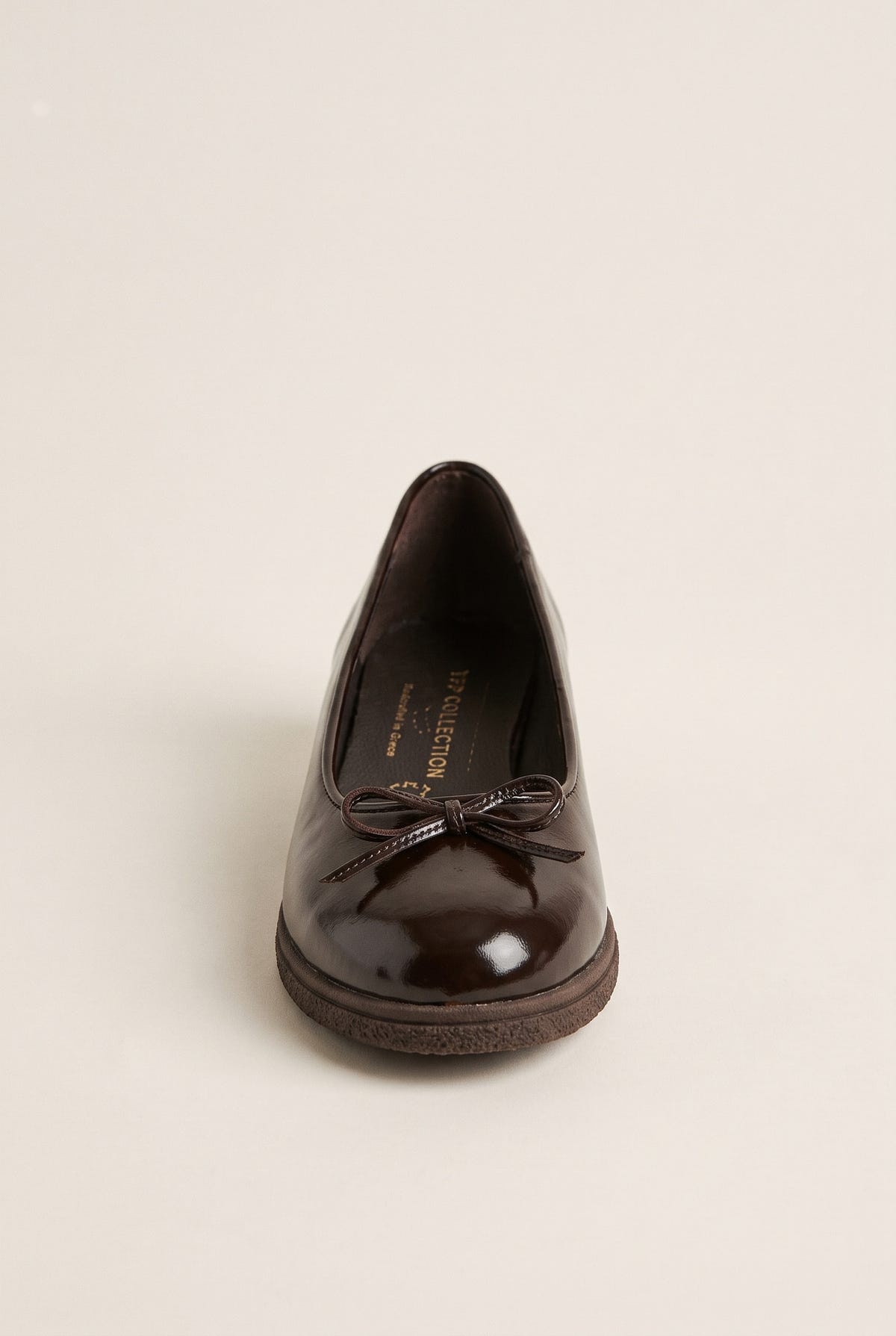 front view of one glossy dark brown patent ballet flat with a small bow on a rounded toe and thick sole