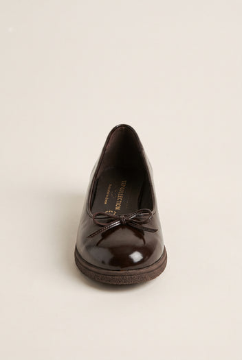 front view of one glossy dark brown patent ballet flat with a small bow on a rounded toe and thick sole