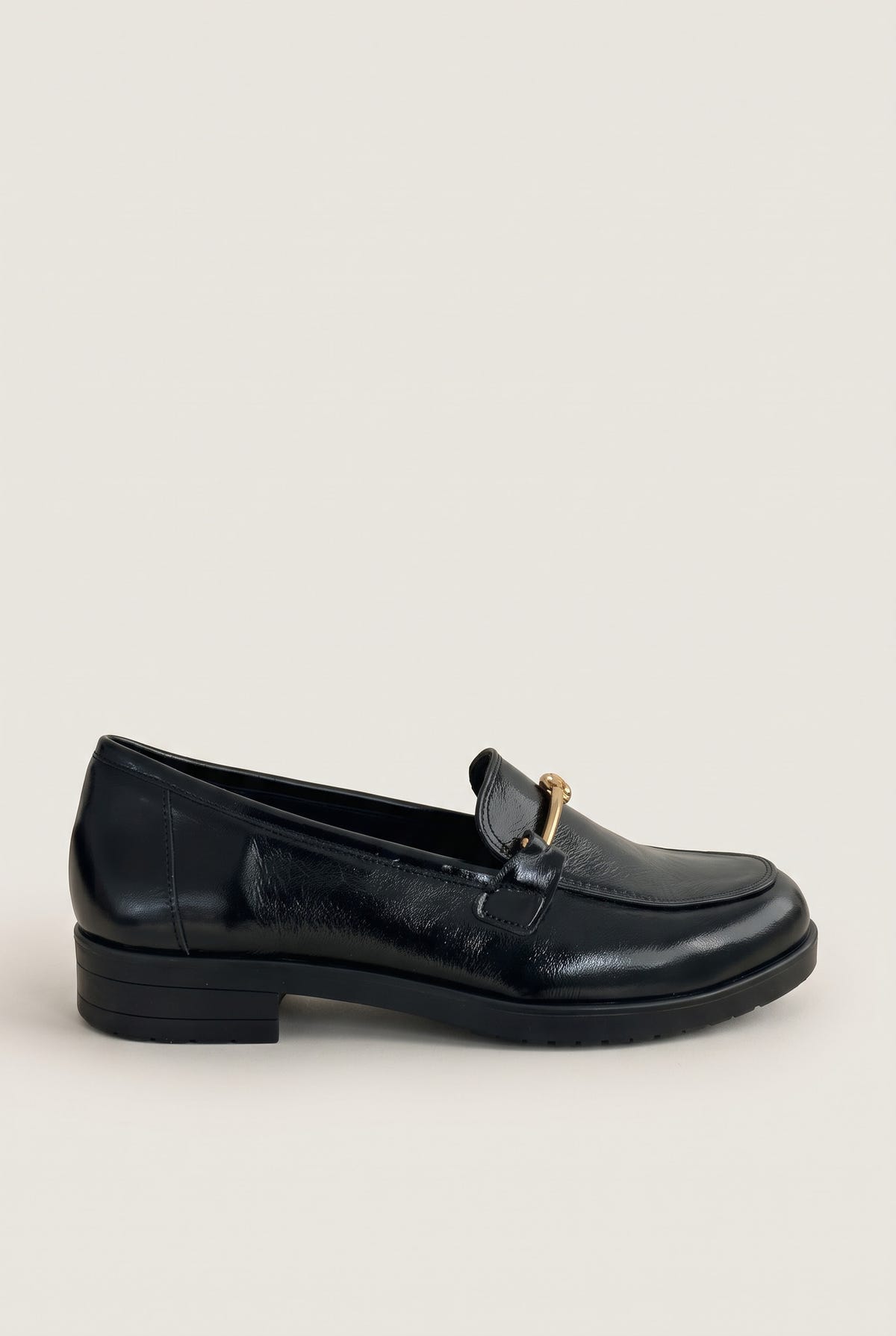 Side view of a single black patent horsebit loafer with gold bar detail and low flat heel