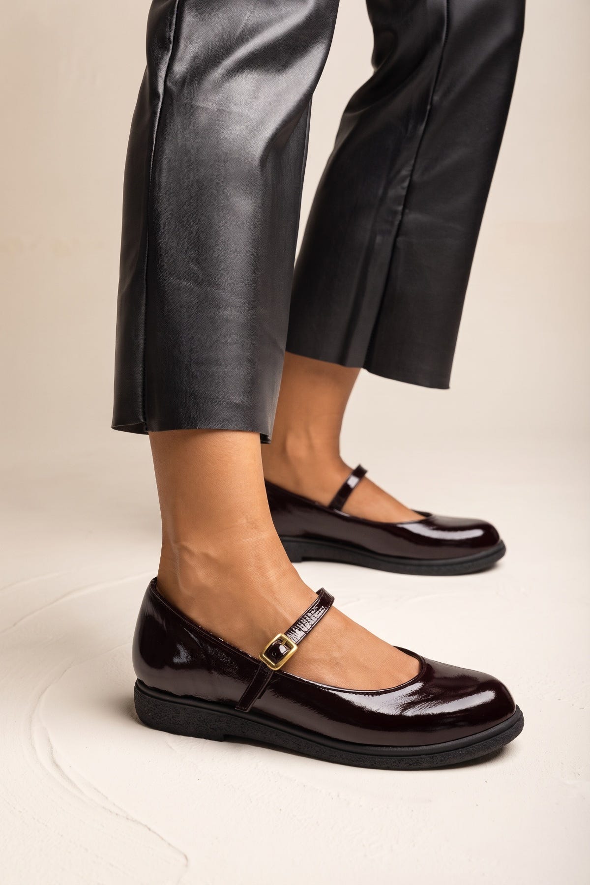 Bordeaux patent Mary Jane flat with ankle strap, worn with black leather trousers