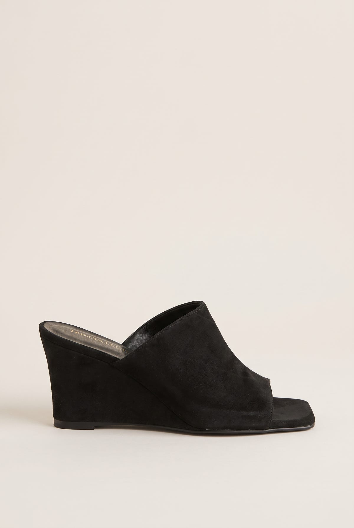 Side view of black suede wedge mule with wide vamp band, square open toe and a solid wedge heel