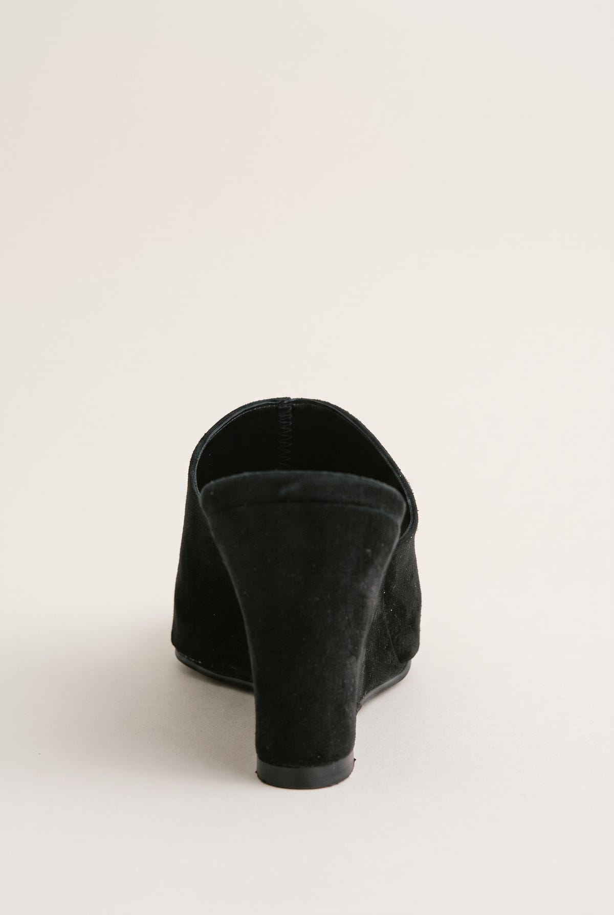 Back view of black suede wedge mule showing the solid wedge heel and wrap-over vamp