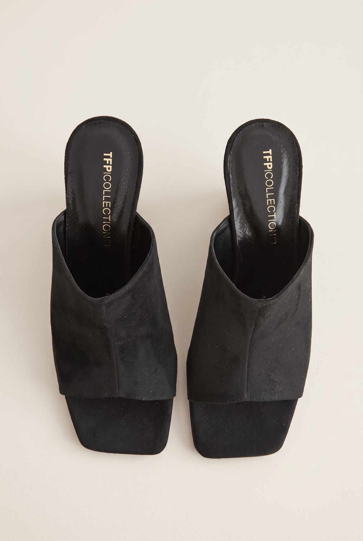 Top view of a pair of black suede mules with wide wrap-over vamps, square open toes and padded footbeds